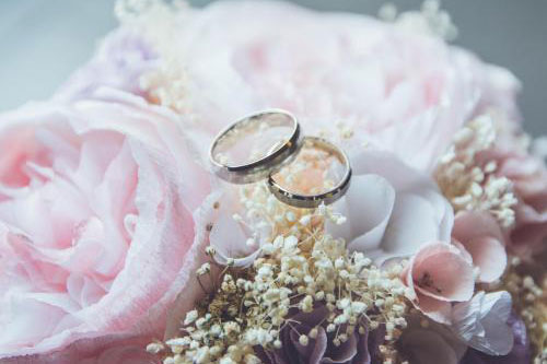 two wedding rings on top of pink roses
