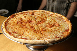 cheese pizza on a platter with slices showing